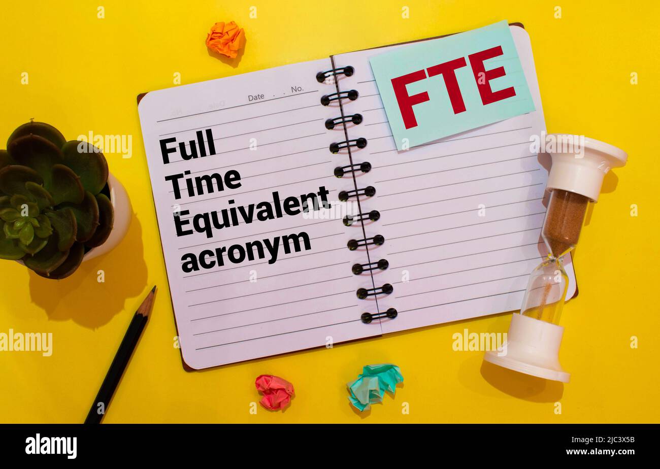 Text FTE Vollzeitschreiben auf Notizbuch mit Bleistift, Uhr, Rechner und Brille auf rotem Hintergrund. Stockfoto