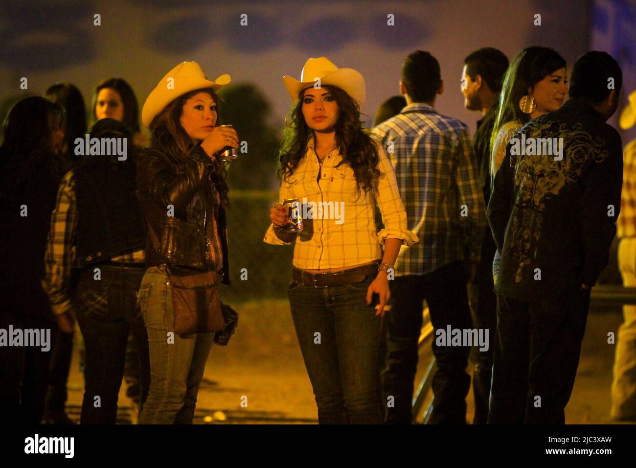 Zwei Frauen trinken eine Flasche Tecate Bier, gekleidet als Cowgirls, beim beliebten Tanz auf der Rennstrecke von Hermosillo im Jahr 2012. (© Foto von Luis Gutiérrez Norte Foto). DOS mujeres toman bote de cerveza tecate vestas de vauqeras en el Baile popular en el hipodromo de Hermosillo 2012. (© Foto por Luis Gutiérrez Norte Photo). Combrero vaquero, Cowboyhut Stockfoto