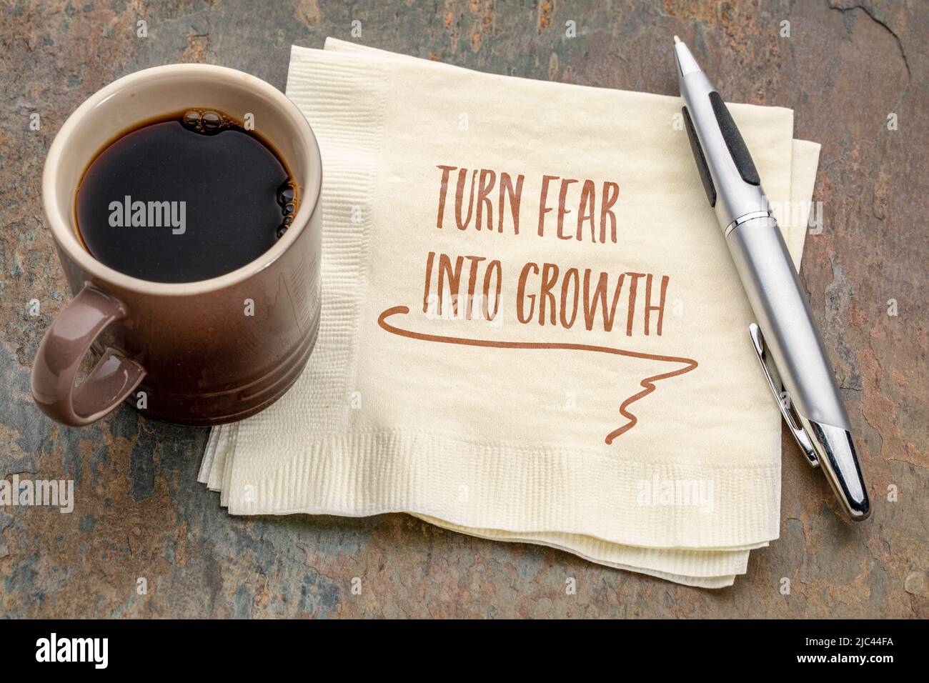 Verwandeln Sie Angst in eine wachstumsinspirierende Note - Handschrift auf einer Serviette mit einer Tasse Kaffee, persönliches Entwicklungskonzept Stockfoto