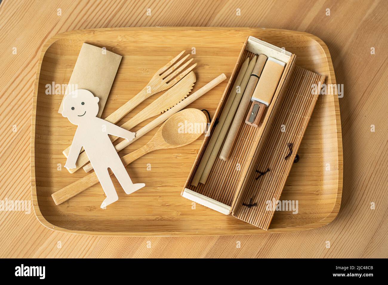 Foto von Öko Konzept der Abfallfreien Produktion, Papier geschnitten fröhlichen Mann mit Holzgeschirr, Stiftetui und Schreibgeräte. Umweltfreundlich Stockfoto