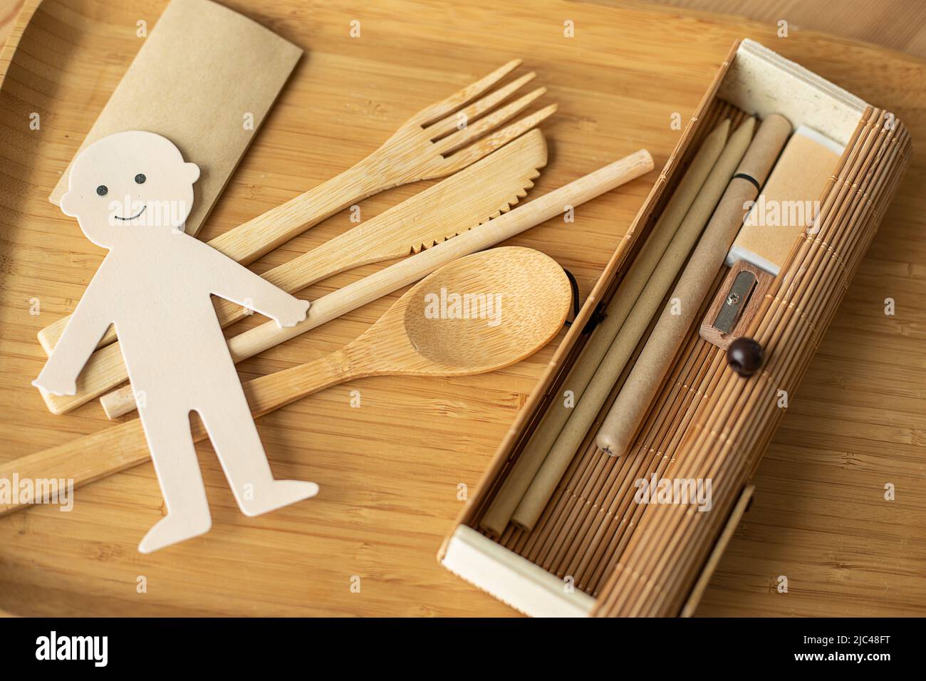 Foto von Öko Konzept der Abfallfreien Produktion, Papier geschnitten fröhlichen Mann mit Holzgeschirr, Stiftetui und Schreibgeräte. Umweltfreundlich Stockfoto