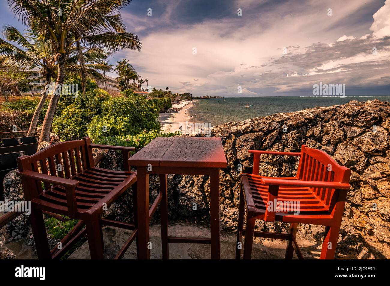 Blick über zwei Stühle mit Tisch auf den Strand und das Meer. Sonnenuntergang am Indischen Ozean, Nyali Beach, Mombasa, Kenia Stockfoto