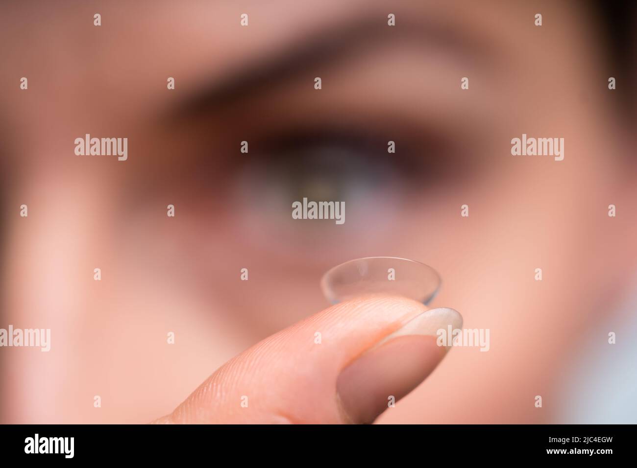 Nahaufnahme einer Frau, die eine transparente Kontaktlinse in ihrem Finger hält Stockfoto
