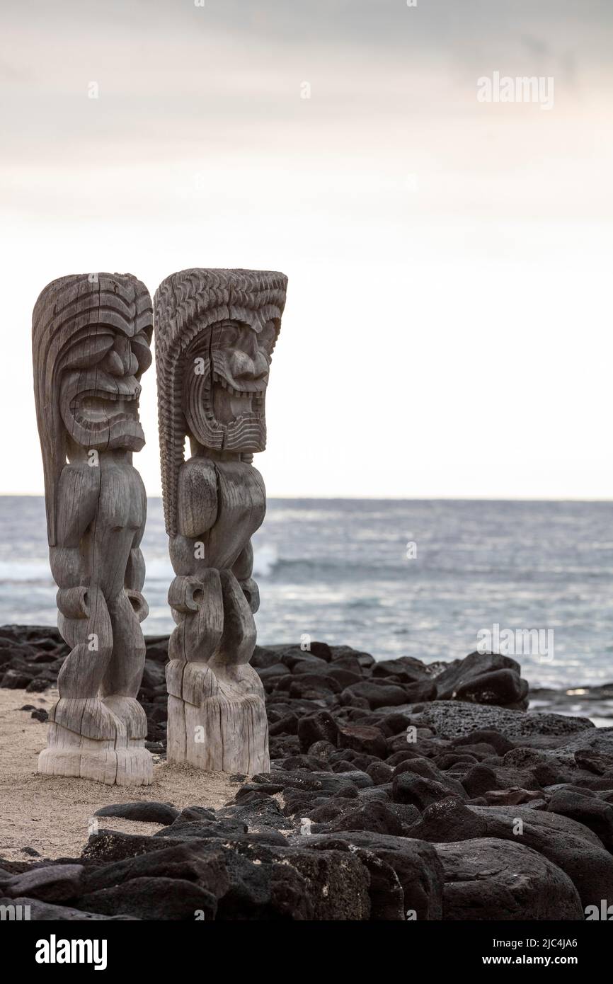 Hölzerne Schutzfigur, Tiki vor der Wand aus Lavasteinen und dem Pazifischen Ozean, Puuhonua O Honaunau National Historical Park, Big Island, Hawaii Stockfoto