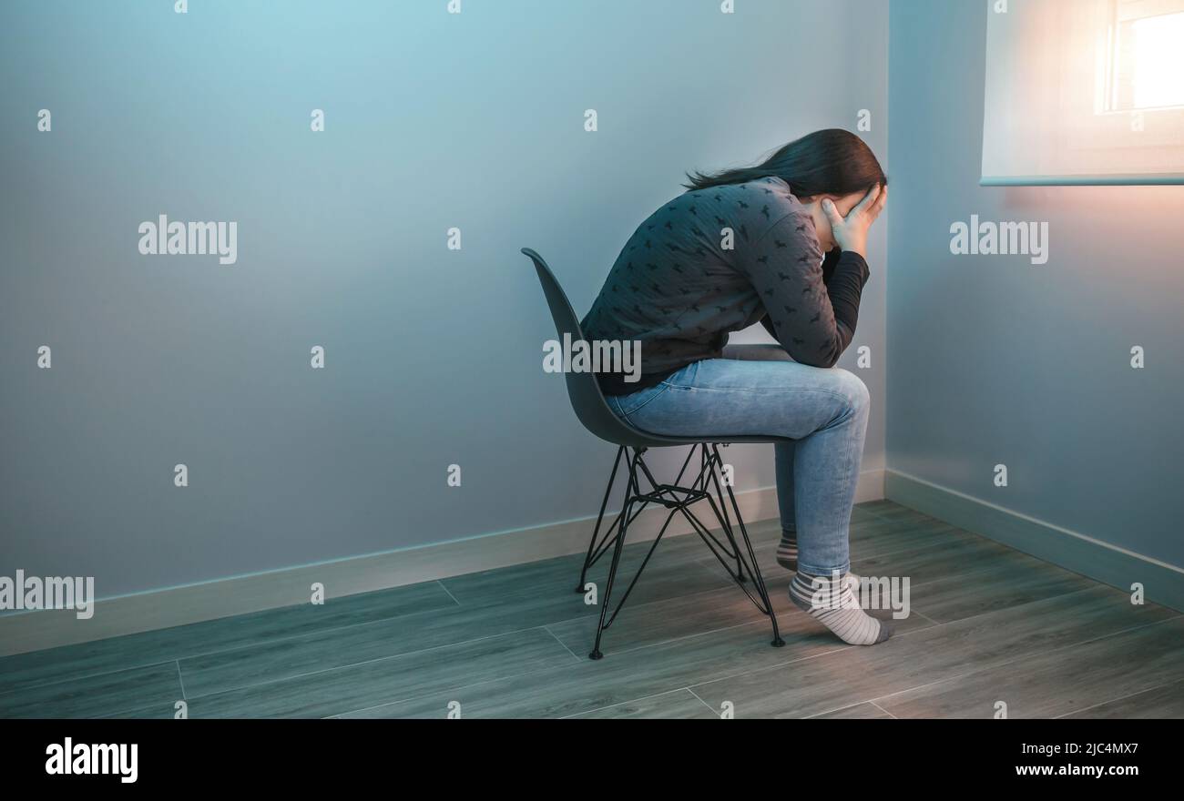 Besorgte Frau mit psychischen Problemen auf einem Stuhl sitzen Stockfoto