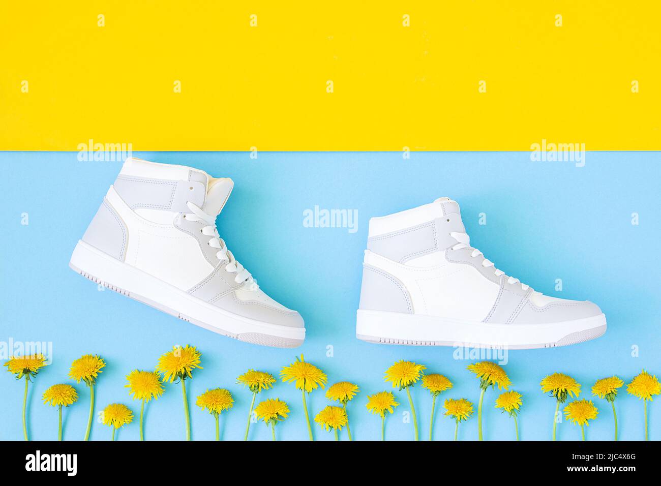 Schuhe und gelbe Blumen auf blaugelbem Hintergrund. Schritt für Schritt in flacher Optik. Erfolg und Entwicklung kreatives Konzept. Draufsicht. Stockfoto
