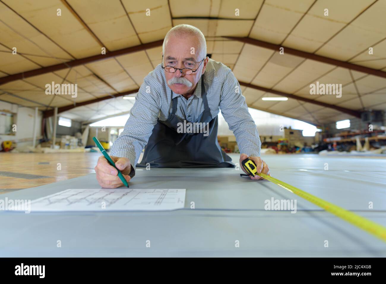 Qualifizierter, leitender Zimmermann, der präzise Blueprint-Messungen durchgeführt hat Stockfoto