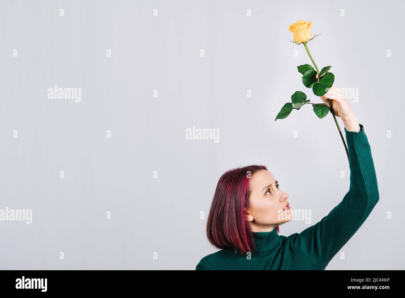 Frau mit einer gelben Rosenblume in der Hand auf hellem Hintergrund. Stockfoto