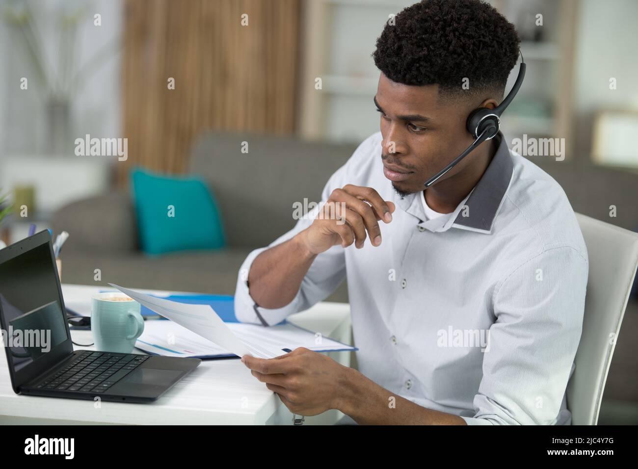 Schwarzer, männlicher Callcenter-Mitarbeiter, der auf den Bildschirm schaut Stockfoto