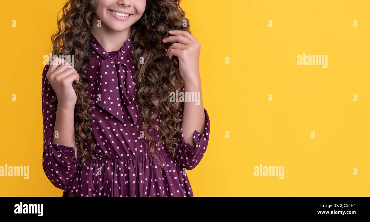 Positives Kind im Strohhut mit langen brünetten lockigen Haaren auf gelbem Hintergrund Stockfoto