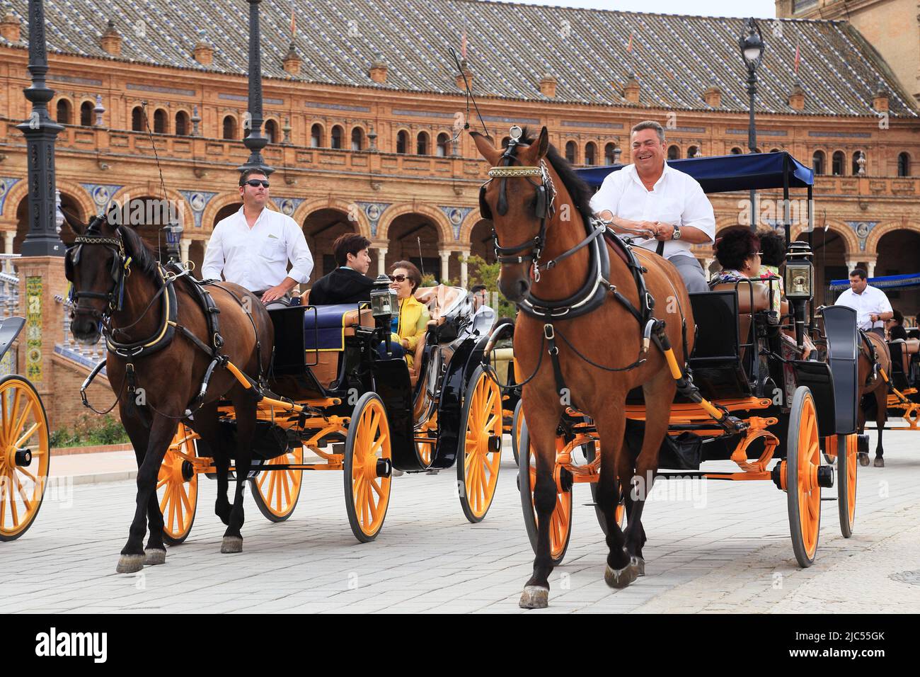 SEVILLA, SPANIEN - 21. MAI 2017: Es gibt eine retro-Pferdekutschen mit Touristen auf einer Tour durch den Spanien-Platz. Stockfoto SEVILLA, SPANIEN - 21. MAI 2017: Es gibt eine retro-Pferdekutschen mit Touristen auf einer Tour durch den Spanien-Platz. Stockfoto