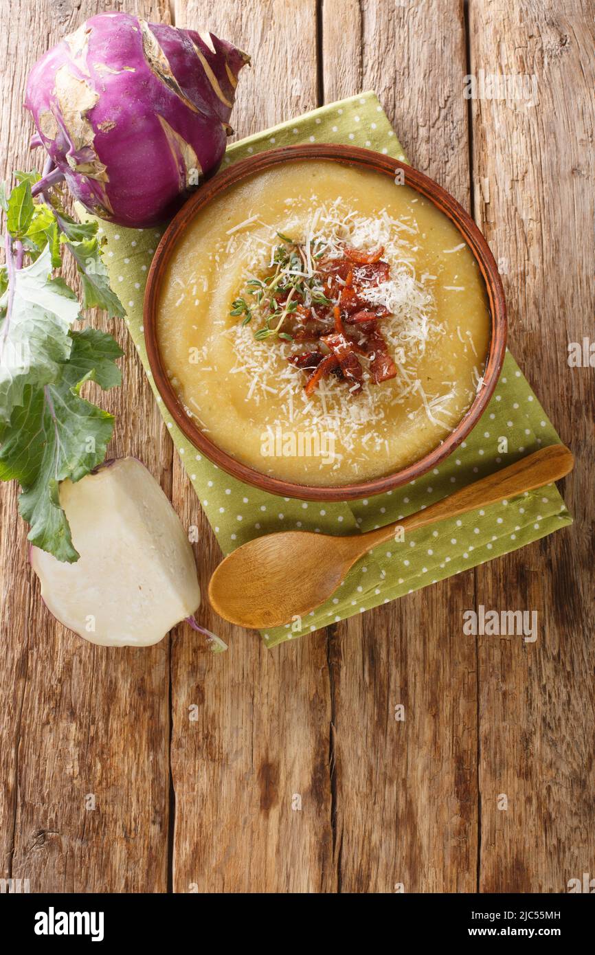 Cremige Kohlrabi-Suppe mit Speck und Parmesankäse in einer Schüssel auf dem Tisch. Vertikale Draufsicht von oben Stockfoto