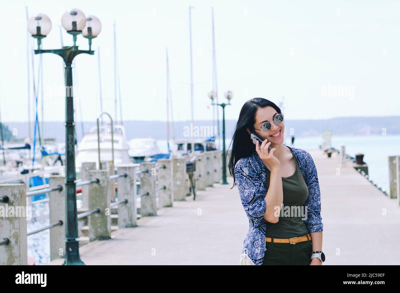Porträt einer jungen glücklichen Geschäftsfrau, die sich in der Stadt entspannt, Park an der Adria. Über Telefon. Selfie.-Technologie. Soziale Medien. Videoanruf. Sommer Stockfoto