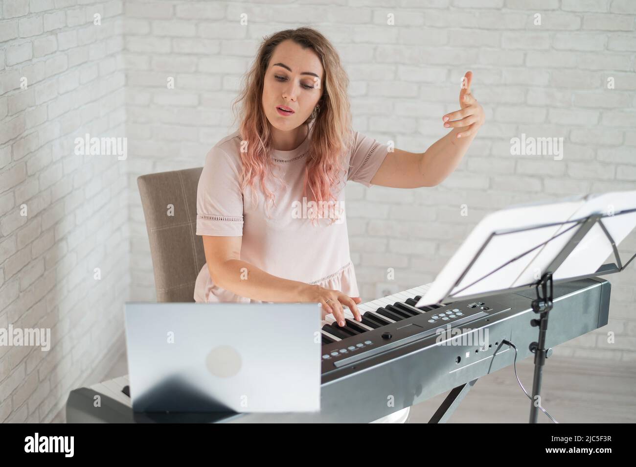 Ferngesteuerte Musikunterricht. Ein singender Lehrer zeichnet die Lektion auf einer Laptop-Webcam auf. Stockfoto