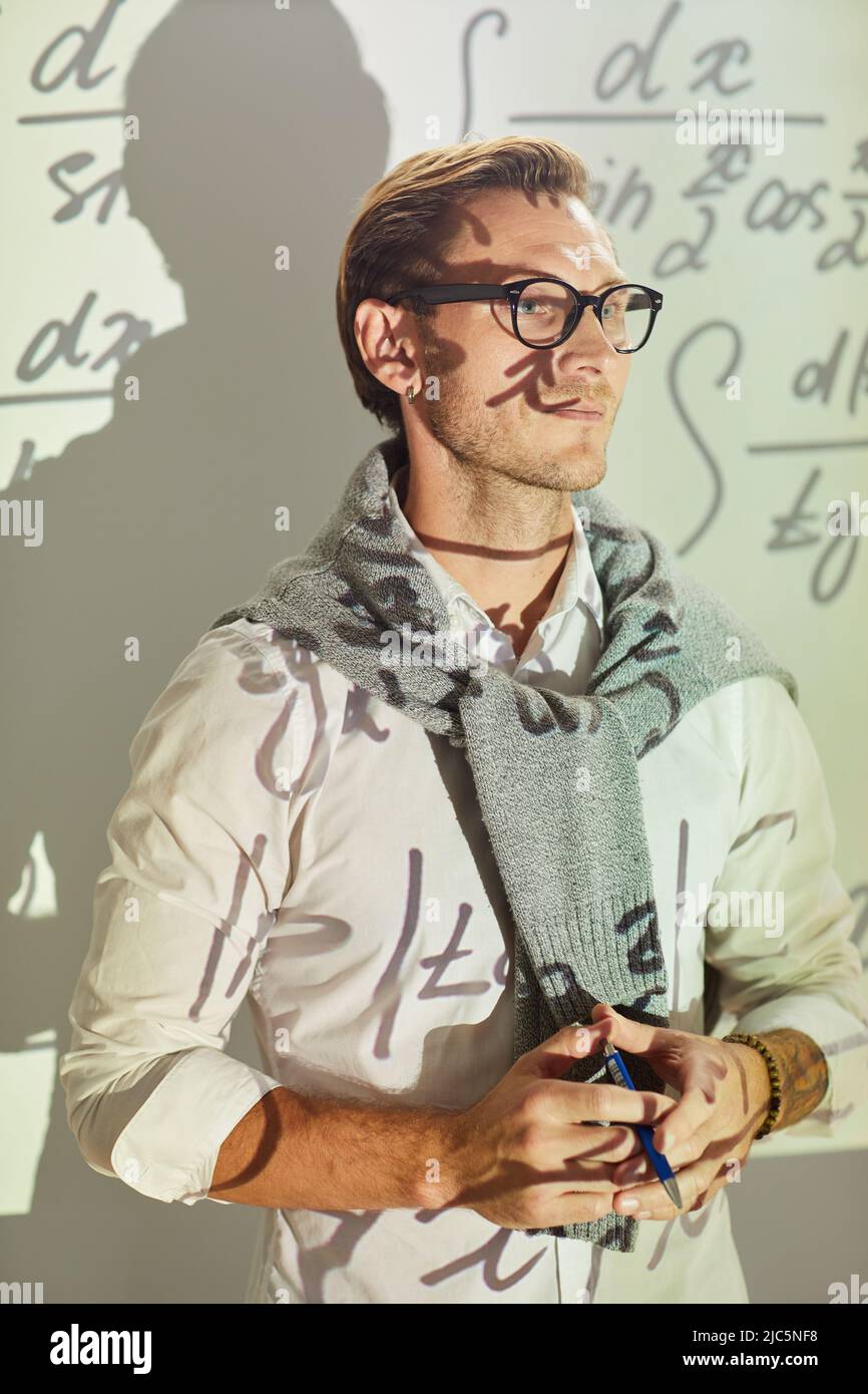 Inhalt gutaussehender junger Analytiker in elegantem Casual-Outfit, der gegen die Projektionsleinwand steht und den Stift in den Händen hält Stockfoto