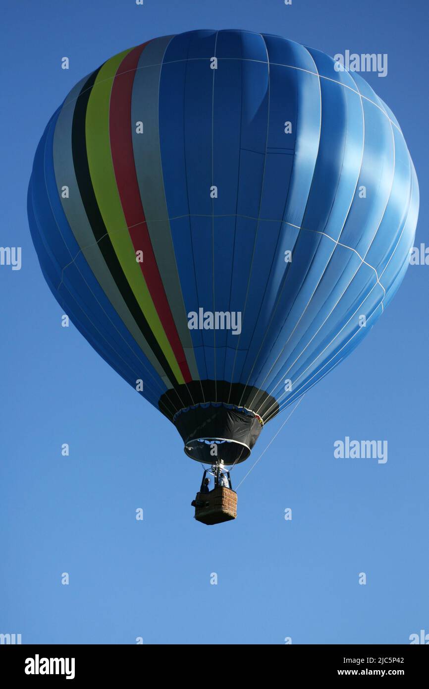 Belgien, Rochefort, Parkdomäne der Grotten von Han. 24.11.2021. Der Heißluftballon hebt sich in den blauen Himmel. Drei Personen befinden sich im Korb. Stockfoto
