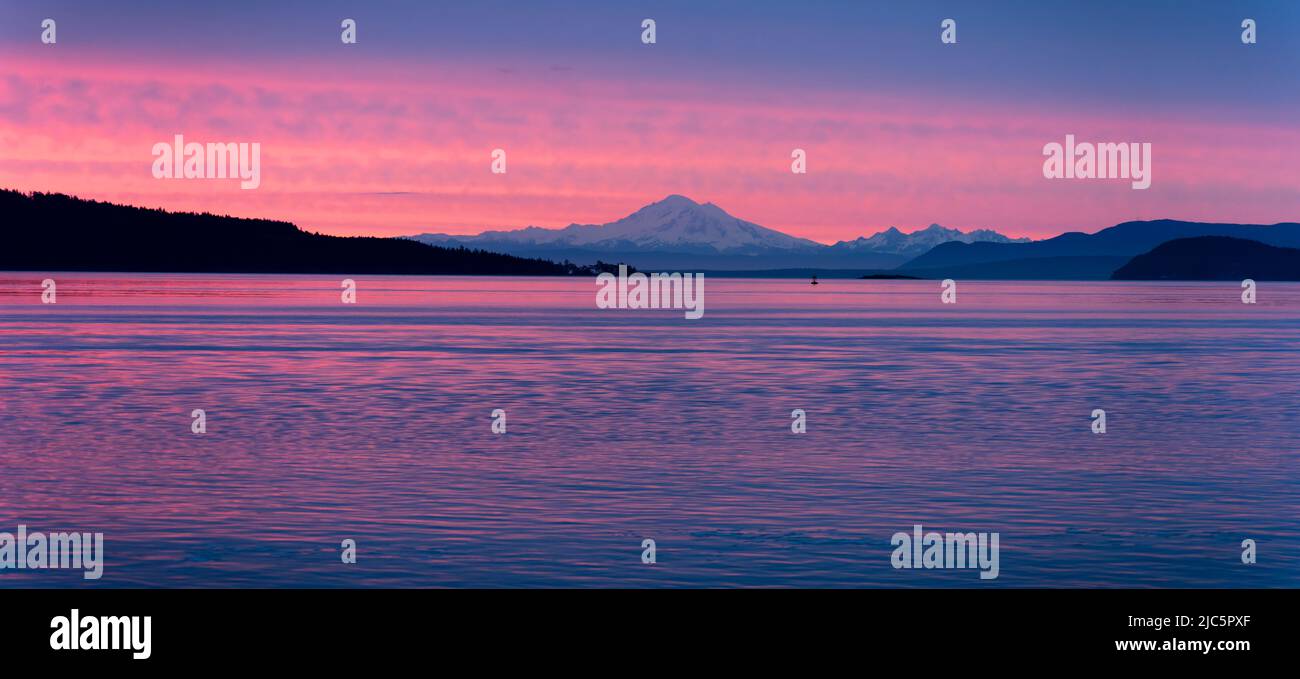 Sonnenaufgang über der Salish Sea und Mount Baker in Washington, von einer Fähre aus gesehen, die durch die südlichen Golfinseln von British Columbia, Kanada, fährt. Stockfoto