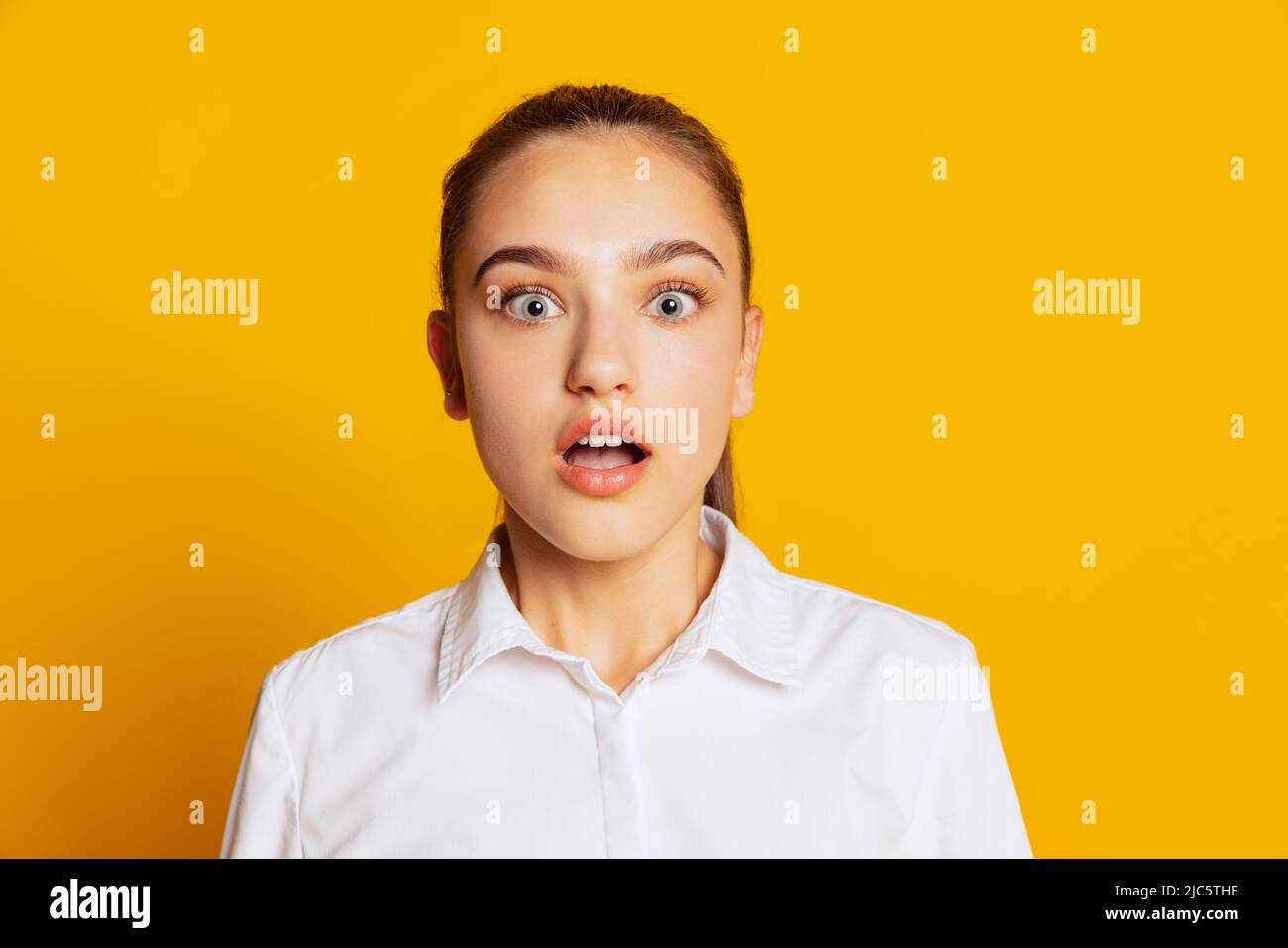 Nahaufnahme Porträt von überrascht Mädchen Blick auf die Kamera mit weit offenen Augen isoliert auf gelbem Hintergrund. Konzept von Schönheit, Kunst, Mode, Gesichtsbehandlung Stockfoto