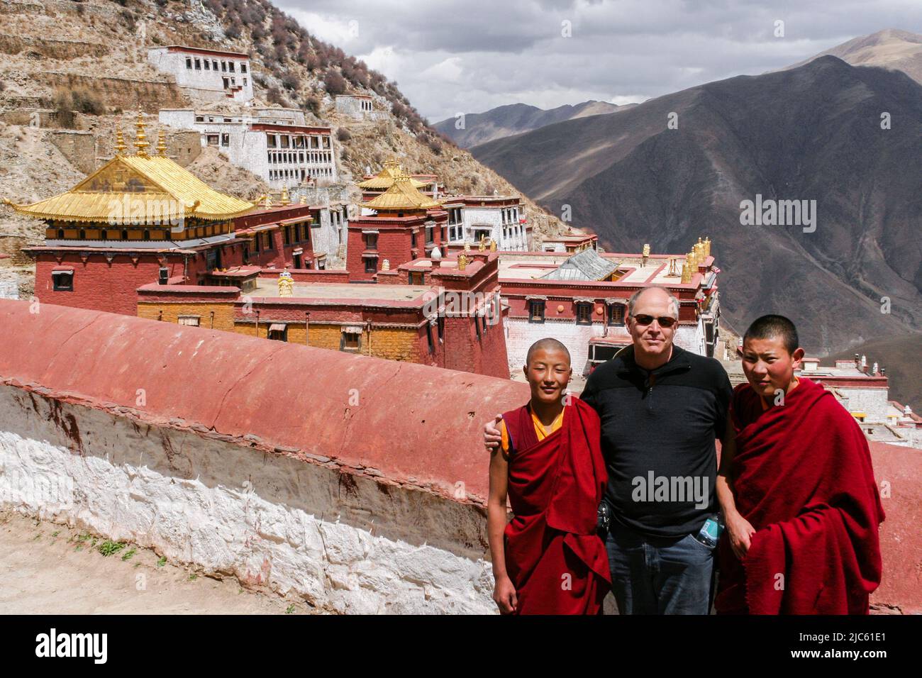 Ein Tourist mit zwei jungen Mönchen im Kloster Ganden auf dem Berg Wangbur, dem 1.. Jahrhundert und dem Hauptkloster der Gelug-Schule des tibetischen Buddhismus. Stockfoto