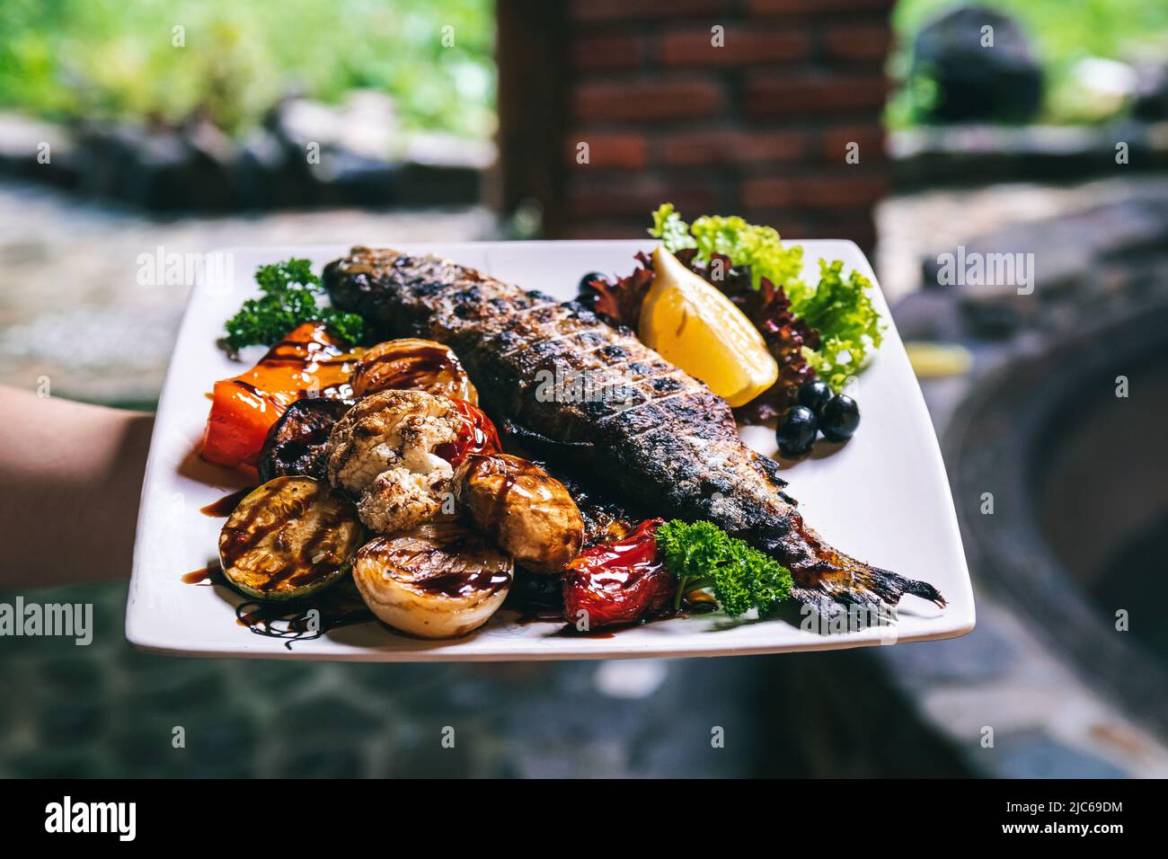 Das Fischgericht wird mit Gemüse, Kartoffeln und Gewürzen gegrillt. Stockfoto