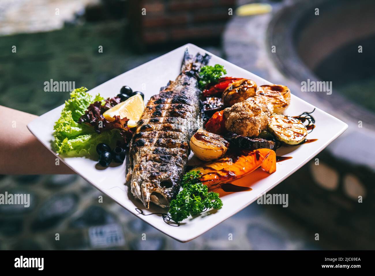 Das Fischgericht wird mit Gemüse, Kartoffeln und Gewürzen gegrillt. Stockfoto