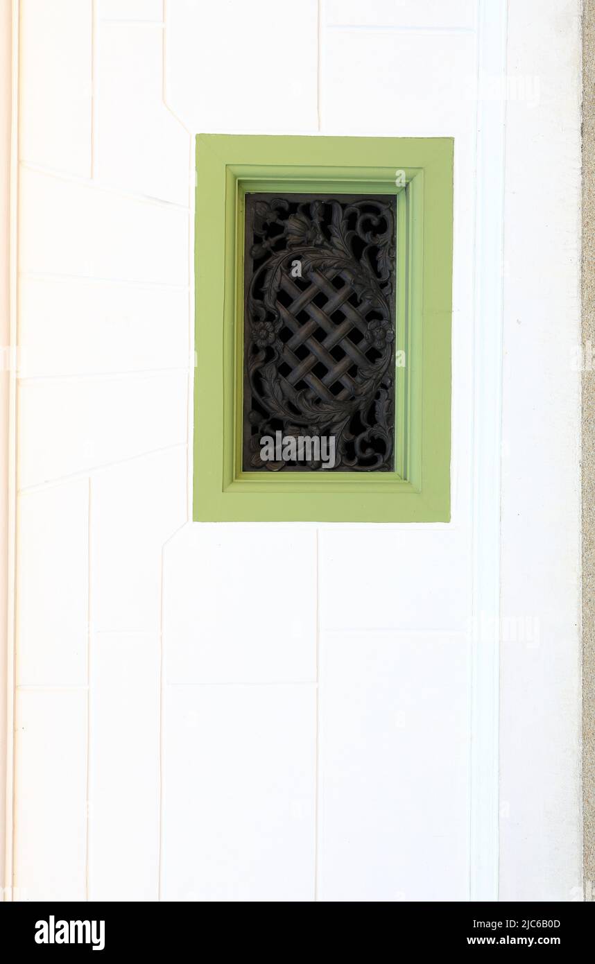 Staubige weiße Fassade eines alten Gebäudes mit einem wunderschönen grünen Holzauslass oder einem Blowhole. Stockfoto