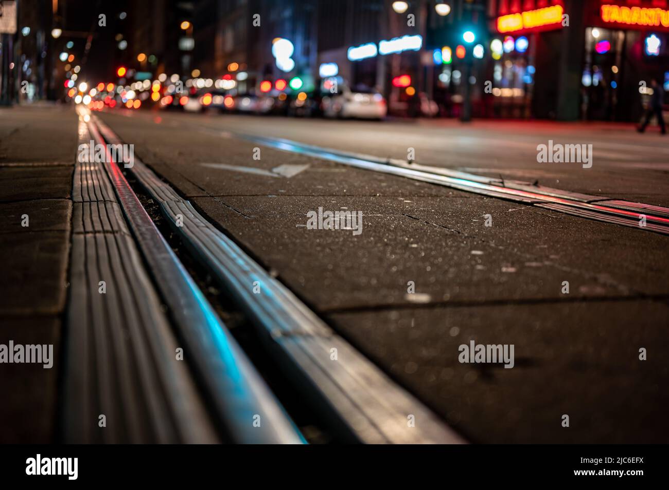 Selektiver Fokus auf Straßenebene auf Trolley-Bahnlinien bei Nacht in San Diego. Stockfoto