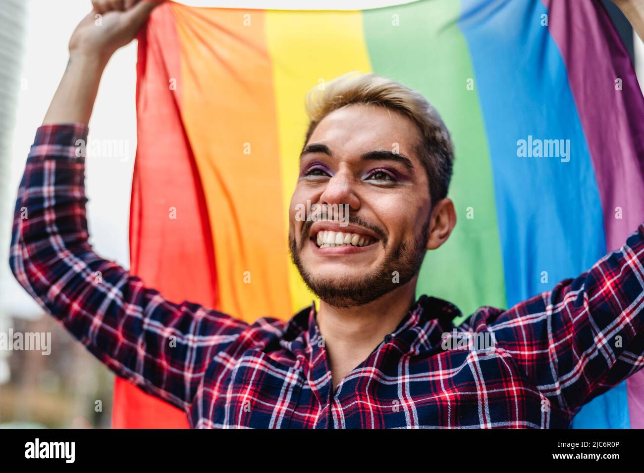 Fröhlicher schwuler Mann feiert das Pride Festival mit dem Symbol der Regenbogenflagge der LGBTQ-Gemeinschaft Stockfoto