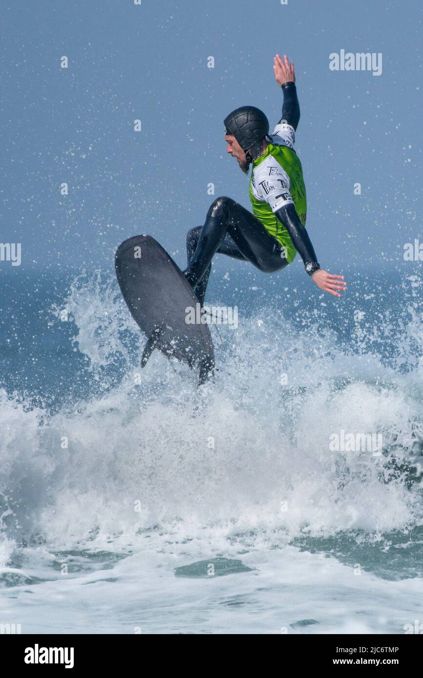Ein Surfer mit Schutzhelm, der an einem Surfwettbewerb im britischen Fistral in Newquay in Cornwall teilhat. Stockfoto