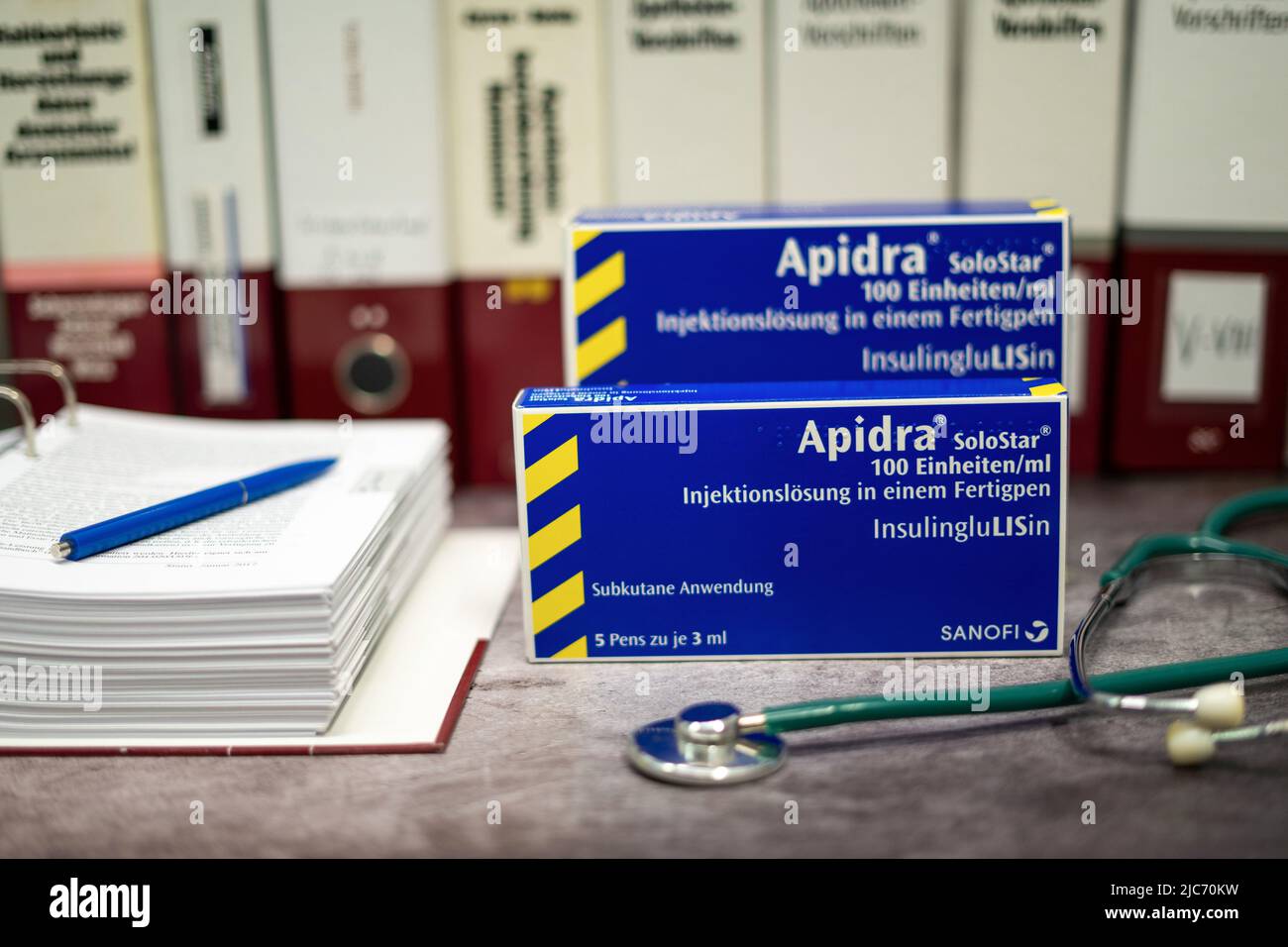 Apidra-Medikament, das schnell wirkendes Insulin zur Behandlung von Diabetes mellitus enthält, auf einem Tisch und im Hintergrund verschiedene medizinische Bücher. Stockfoto
