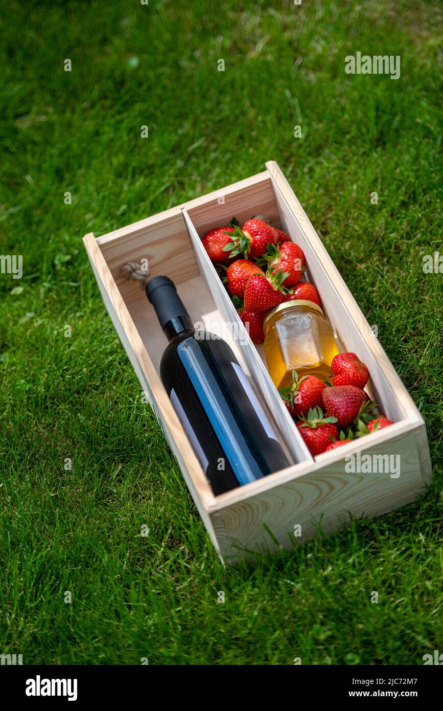 Sommerfeeling auf grünem Gras mit Früchten, Wein und Honigdeko als Geschenk für Hochzeit und Geburtstag. Naturrasen frischen Hintergrund sonnig Stockfoto