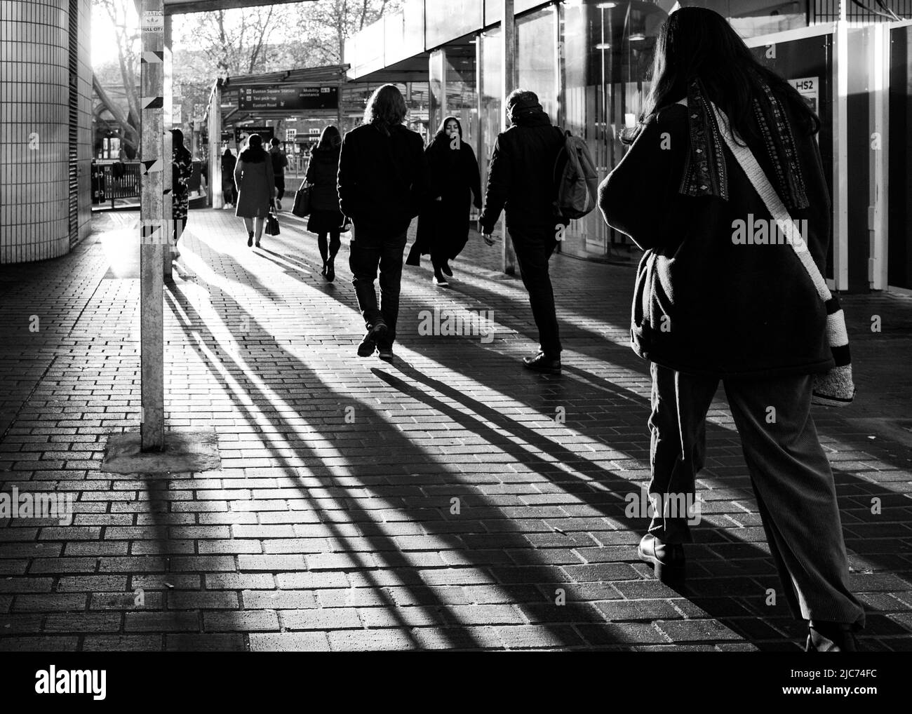 Die Morgensonne wirft lange Schatten auf Pendler, wenn sie den Bahnhof Euston, London, während der morgendlichen Hauptverkehrszeit verlassen. Stockfoto