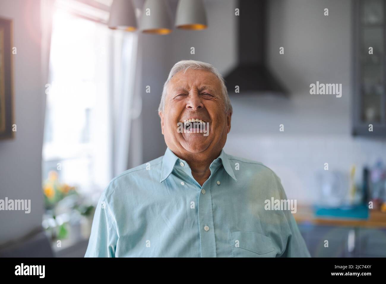 Glücklicher älterer Mann, der in seinem Haus lacht Stockfoto