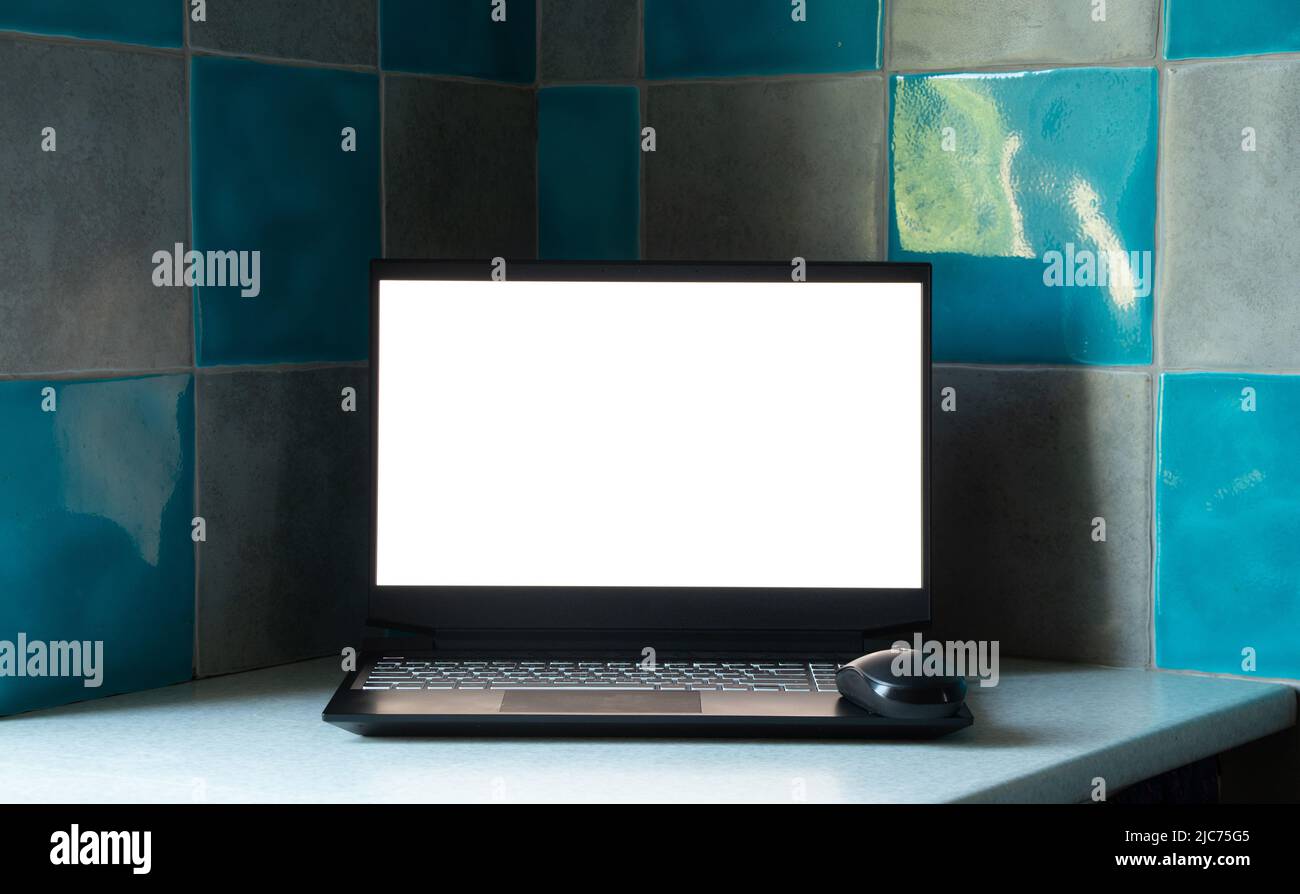 Schwarzer Laptop mit weißem Bildschirm steht in der Küche auf dem Tisch zu Hause, Laptop mit weißem Bildschirm, Vorlage, Laptop auf dem Tisch Stockfoto