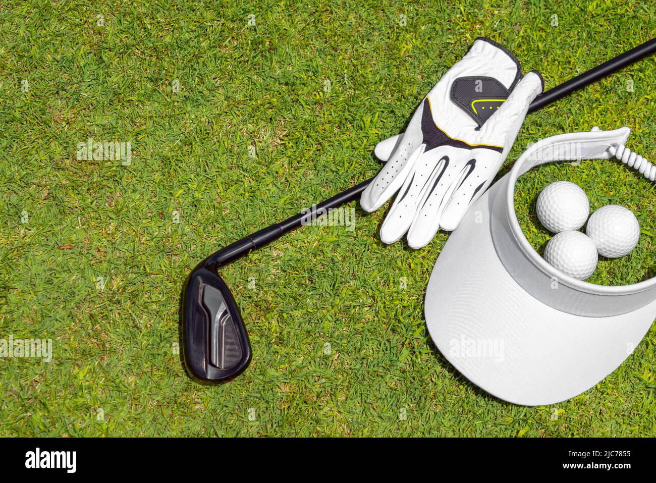 Blick von oben auf die Golfausrüstung auf grünem Gras auf einem Golfplatz. Flache Verlegung von Golfschläger, Bällen, Handschuh und Mütze Stockfoto