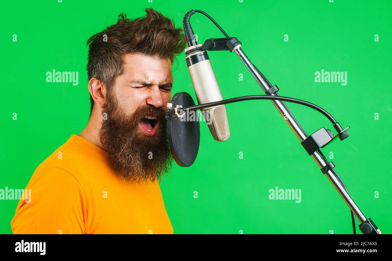 Professioneller Sänger singt im Kondensatormikrofon. Konzept der Musikproduktion. Bärtiger Mann, der singt. Stockfoto