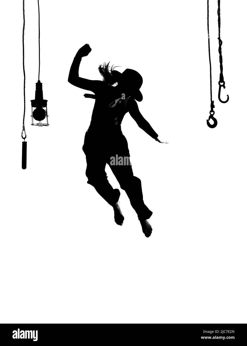 Eine Tänzerin wird auf der Bühne getanzt. In Herrenbekleidung gekleidet und mit einem Männerhut bekleidet, sieht man sie als Silhouette in der Luft springen. Stockfoto