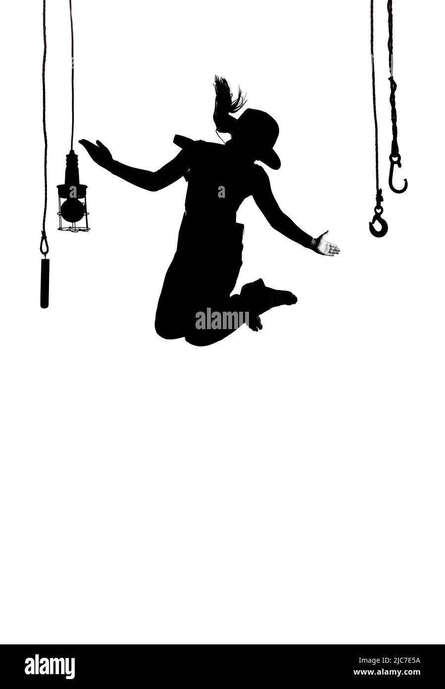 Eine Tänzerin wird auf der Bühne getanzt. In Herrenbekleidung gekleidet und mit einem Männerhut bekleidet, sieht man sie als Silhouette in der Luft springen. Stockfoto