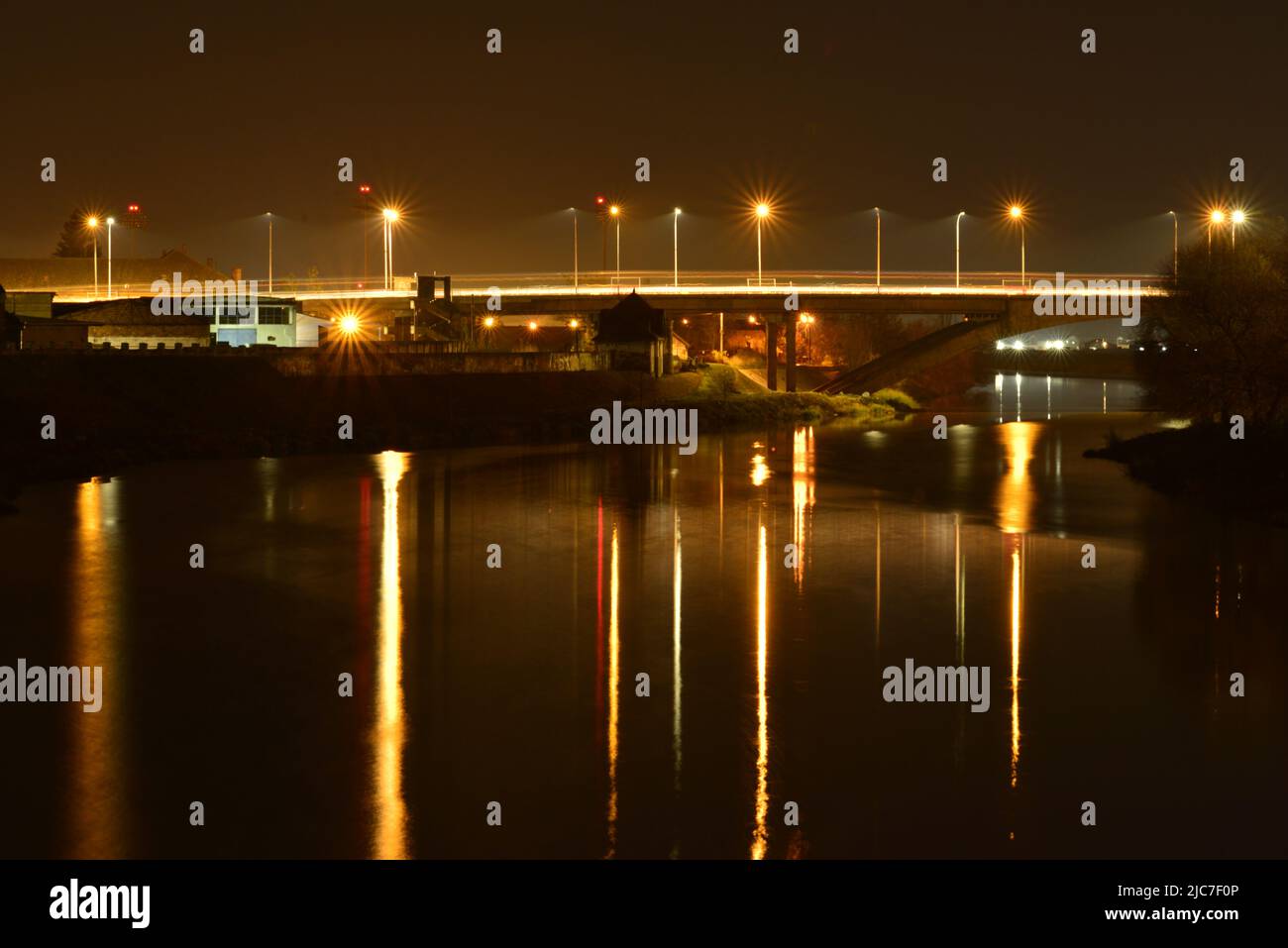 Nachtlandschaft mit Brücke und Lichtreflexen auf dem Flusswasser Stockfoto