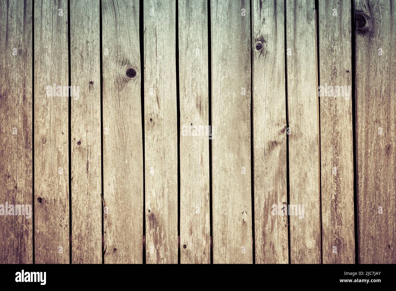 Hellbraune Holzwand mit natürlichen Dielen in verblassener, unebener Struktur. Nahaufnahme des abstrakten blassen Holzzaunhintergrunds. Alte, verwitterte, rissige Bretter. Stockfoto