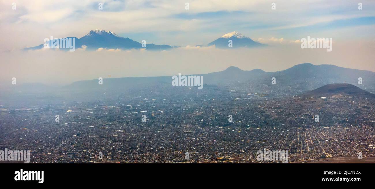 Mexiko-Stadt mit Luftschadstoffschicht und Popocatepetl- und Iztaccíhuatl-Vulkanen im Winter Stockfoto