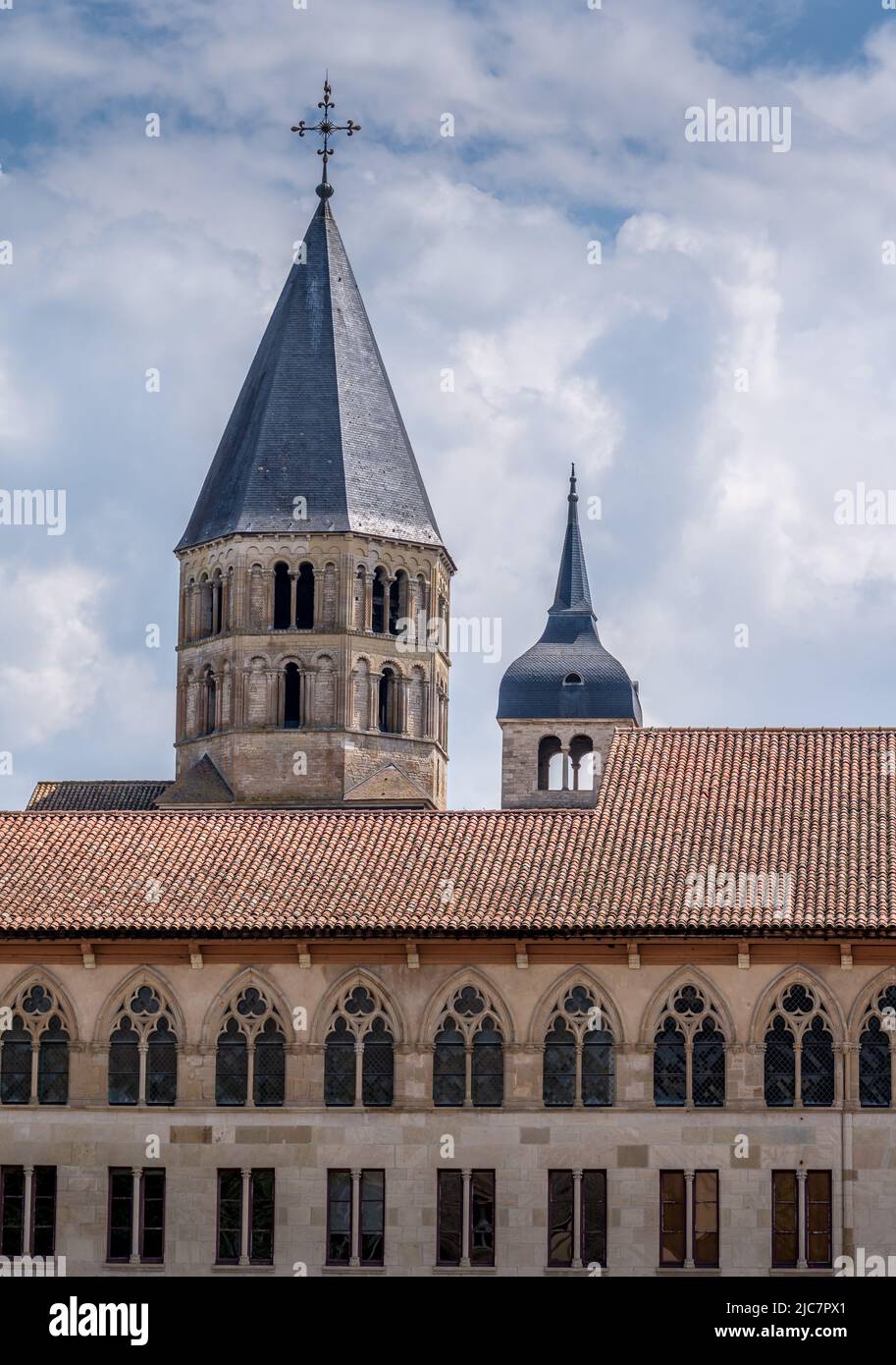 Blick auf eine Reihe gotischer Bogenfenster und einen romanischen Kirchturm mit spitzem Dach im ehemaligen Benediktinerkloster von Cluny France Stockfoto