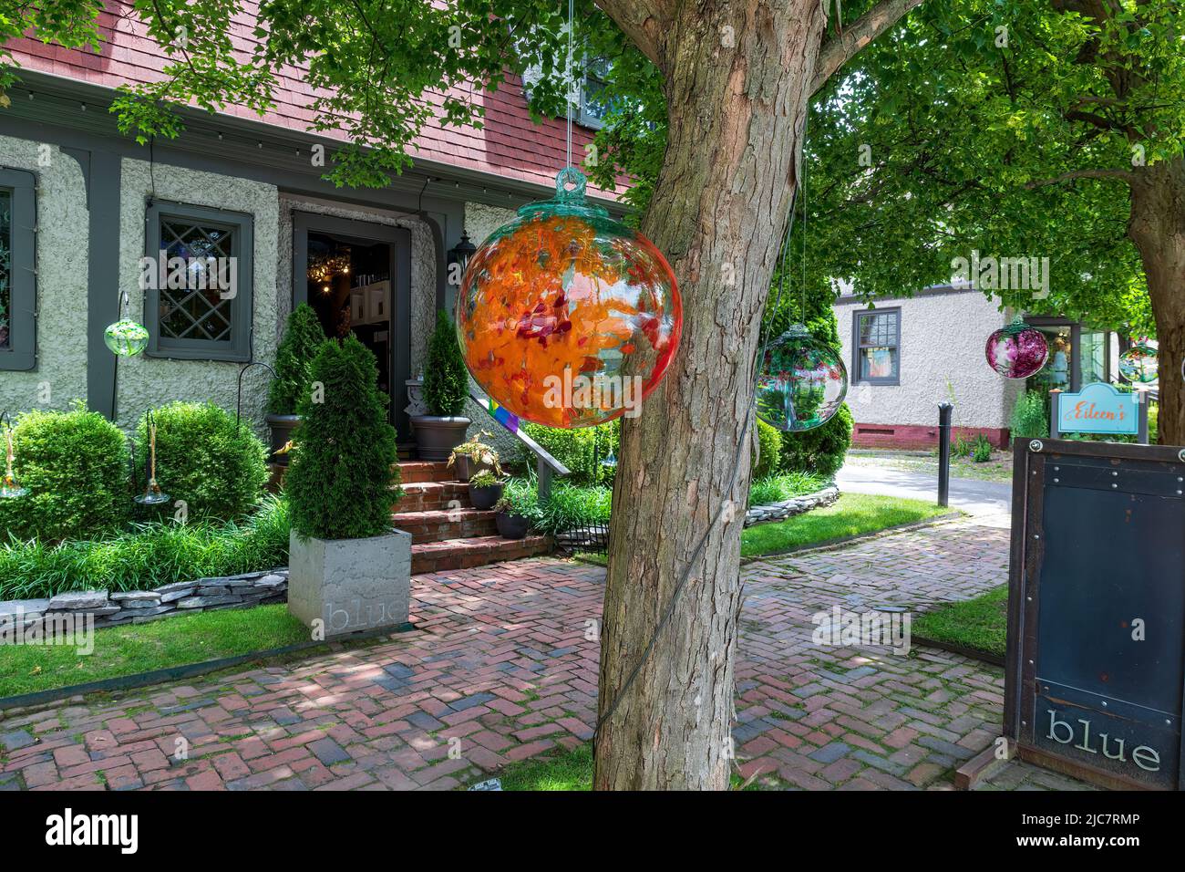 BILTMORE VILLAGE in ASHEVILLE, NC, USA-5 JUNE 2022: The Blue Goldsmith Shop Eingang, mit mehreren bunten Glasgloben hängen im schattigen Vordergrund. Stockfoto