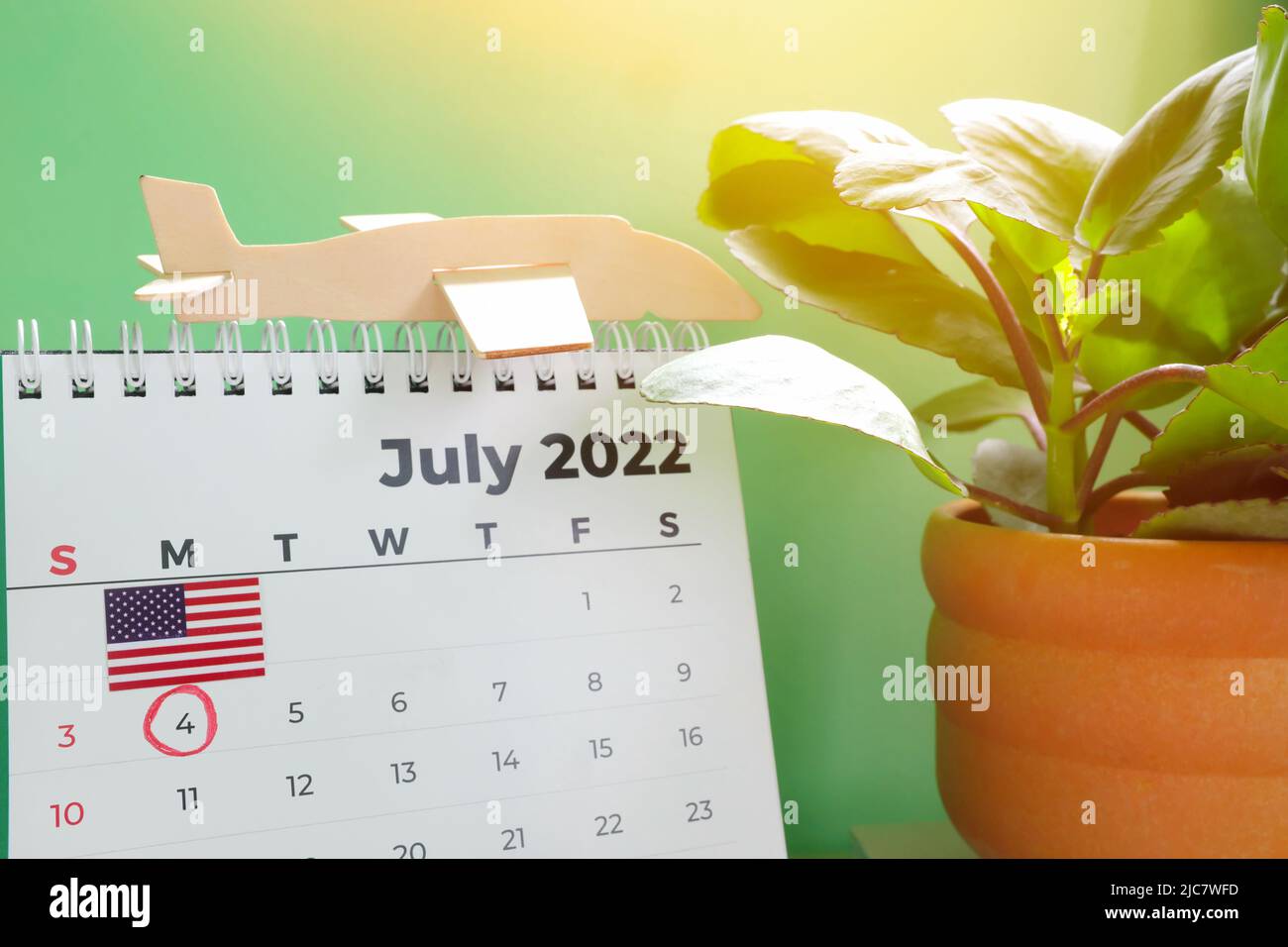 Selektiver Fokus des Tischkalenders Juli 2022 mit markierter Datumsangabe 4.. Juli, Flagge und Flugzeugmodell. Feiertag des Unabhängigkeitstages der Vereinigten Staaten Stockfoto