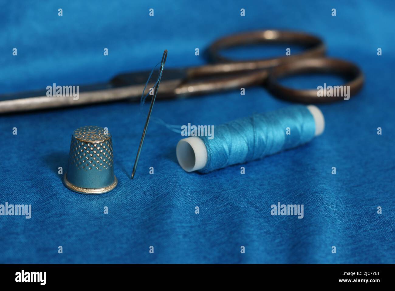 Spule aus blauem Faden, Nimble und Nadel auf blauem Stoff Stockfoto