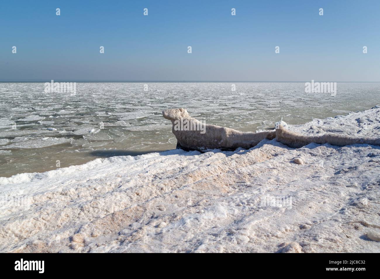Dies ist die gefrorene Küste von Asov mit einer eisigen Surflinie und eisigen Schlamm in der Nähe der Küste. Stockfoto