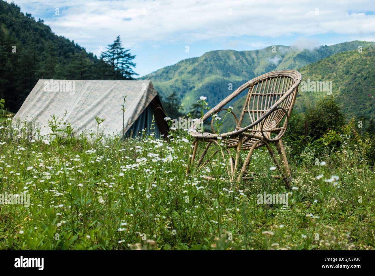 Ein touristischer Ort auf den Wiesen mit einem Camp und einem Bambusstuhl mit Bergen im Hintergrund. Uttarakhand Indien. Stockfoto