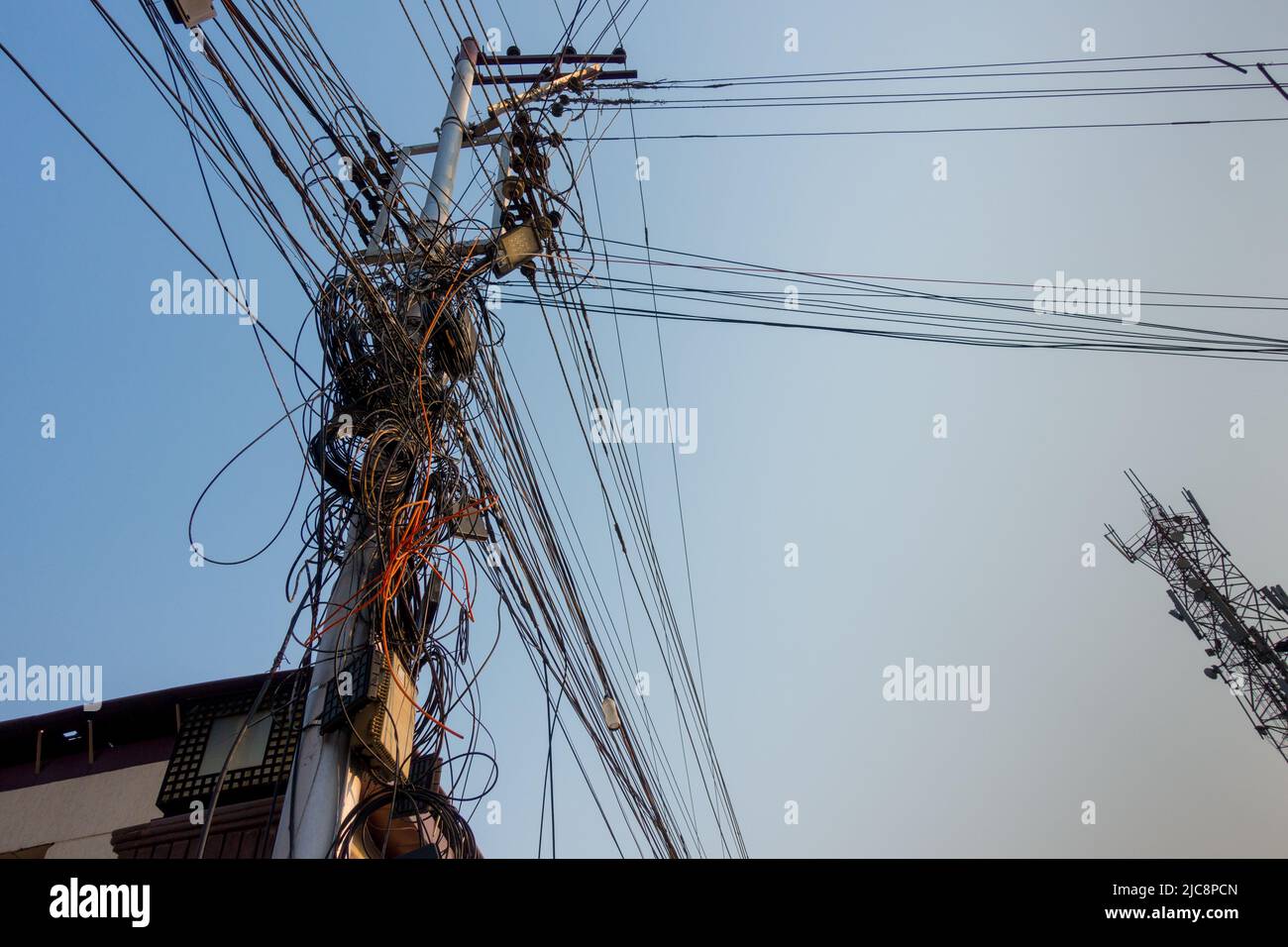Strommasten mit überfüllten Drähten und Verteilerkästen in Indien. Stockfoto