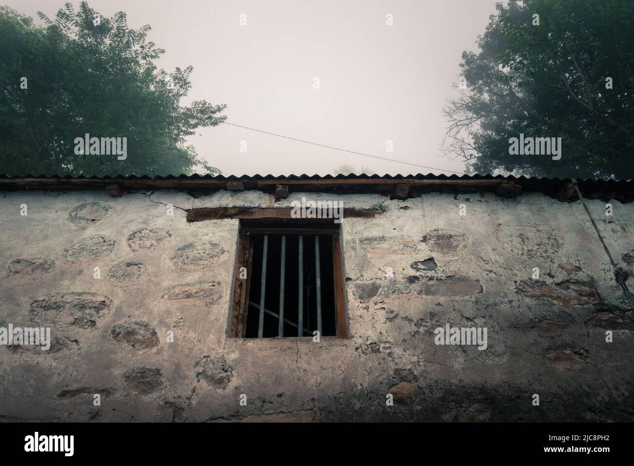 Eine Weitwinkelaufnahme aus eisernem Fenster eines alten und ruhenden traditionellen Hauses aus Steinen im ländlichen indien. Uttarakhand indien. Stockfoto