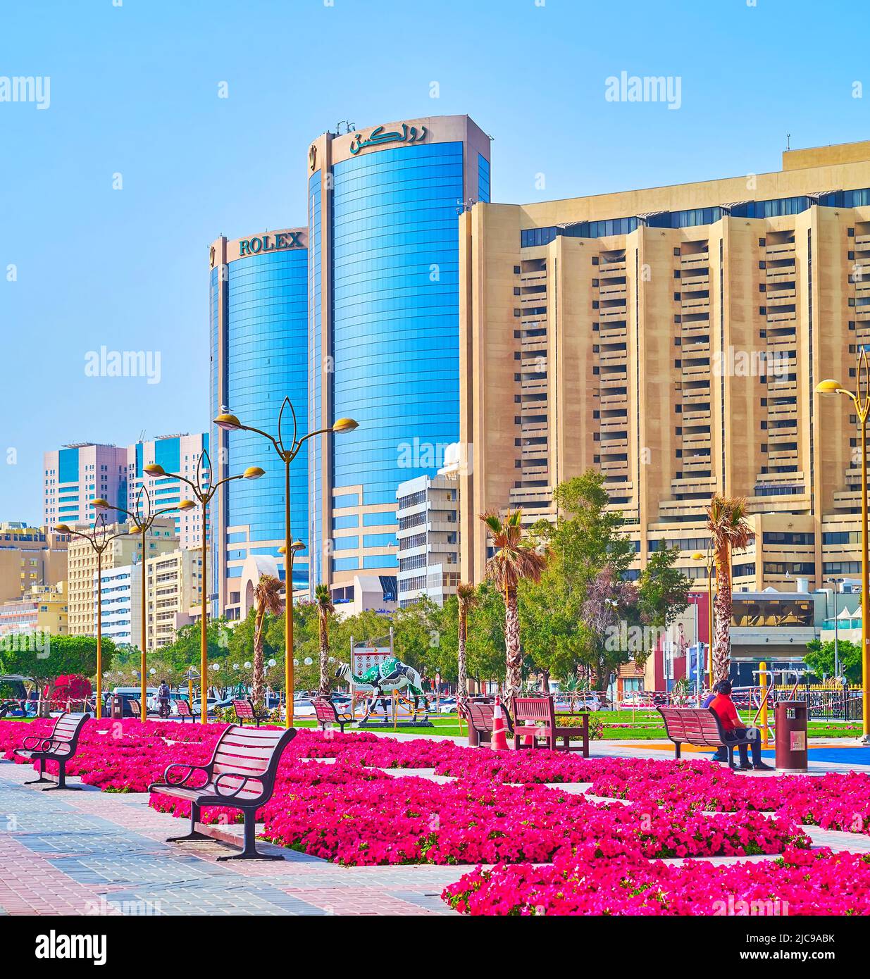 DUBAI, VAE - 1. MÄRZ 2020: Die hellen Stiefmütterchen in Blumenbeeten des Creek Side Park mit Blick auf die Deira Twin Towers (Rolex Towers) im Hintergrund, Port S Stockfoto